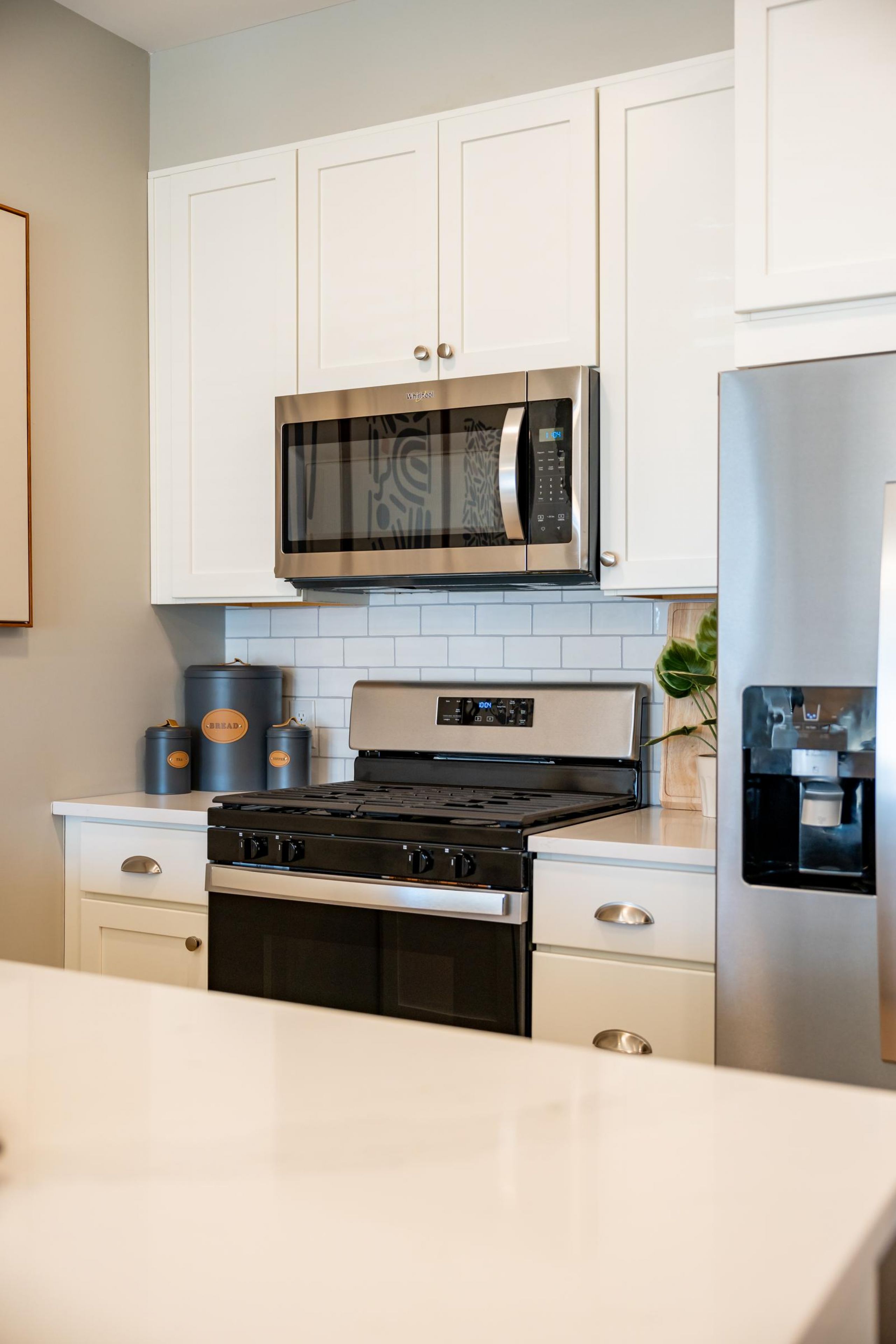 Modern kitchen with white cabinets, stainless steel appliances, and a stove under a microwave.