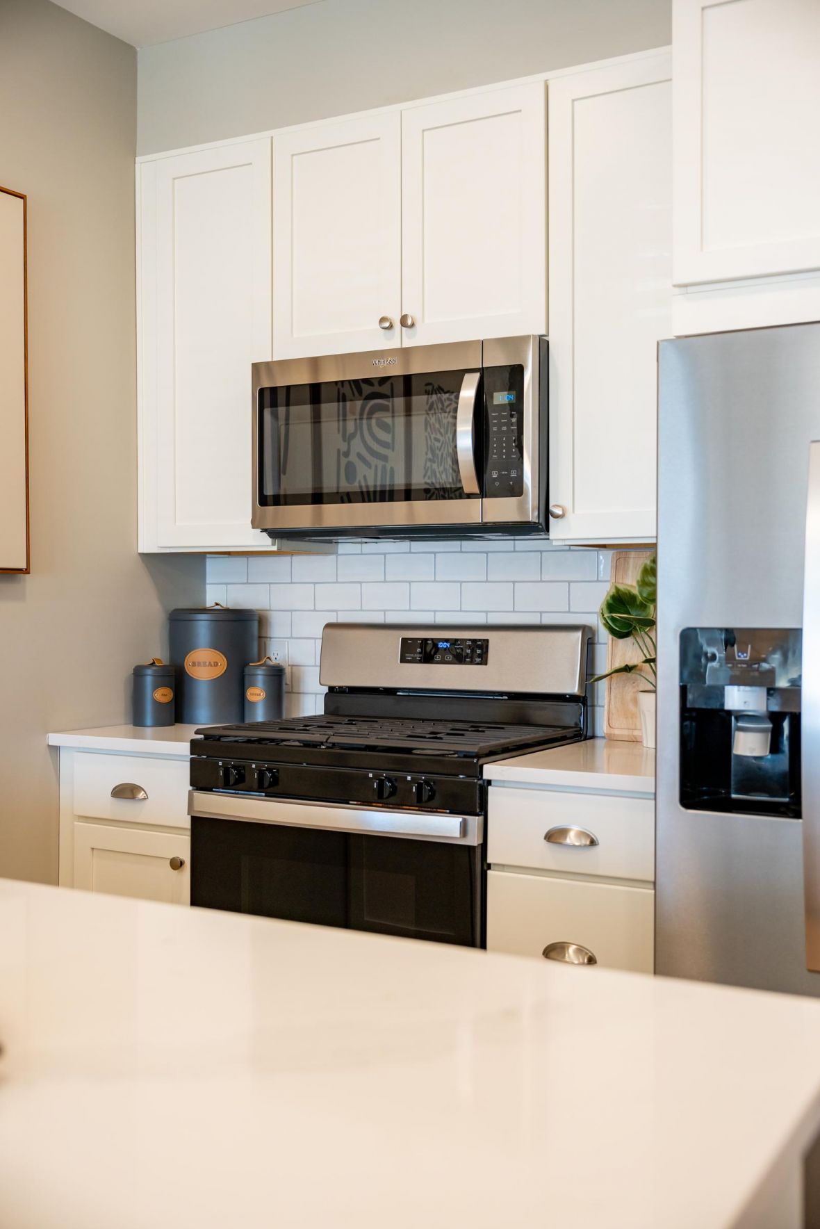 Modern kitchen with white cabinets, stainless steel appliances, and a stove under a microwave.