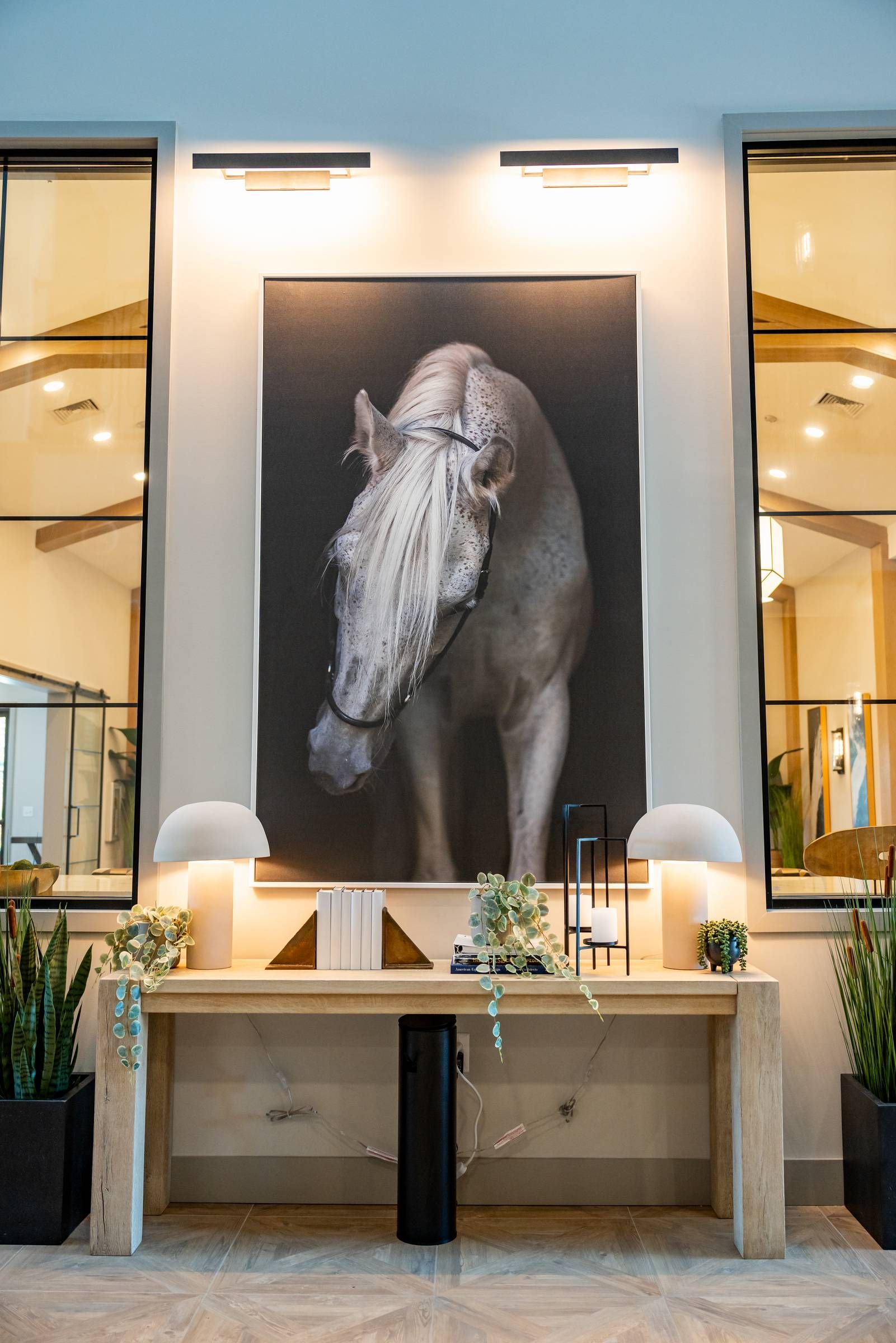 A modern entryway with a console table, decor, and a large framed horse photo on the wall above.