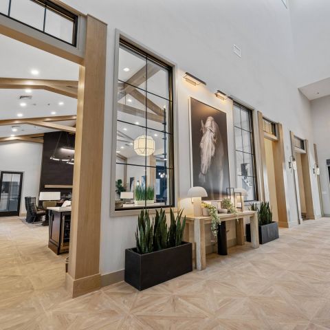 Modern, spacious lobby with wood accents, large windows, plants, and a horse portrait on the wall.